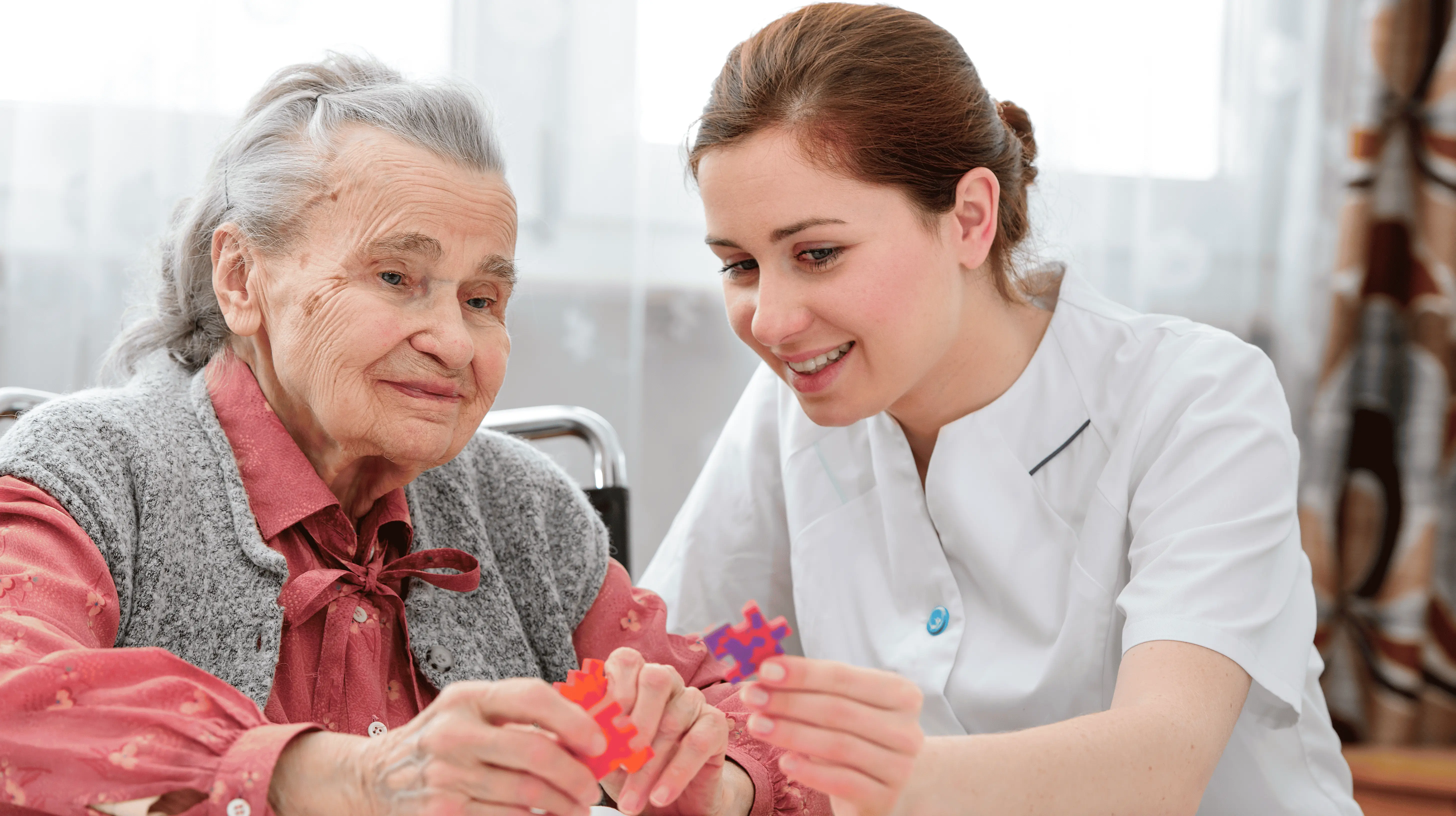 OC HomeCare caregiver helping senior woman with dementia through puzzle-based memory activity at home in Orange County, CA