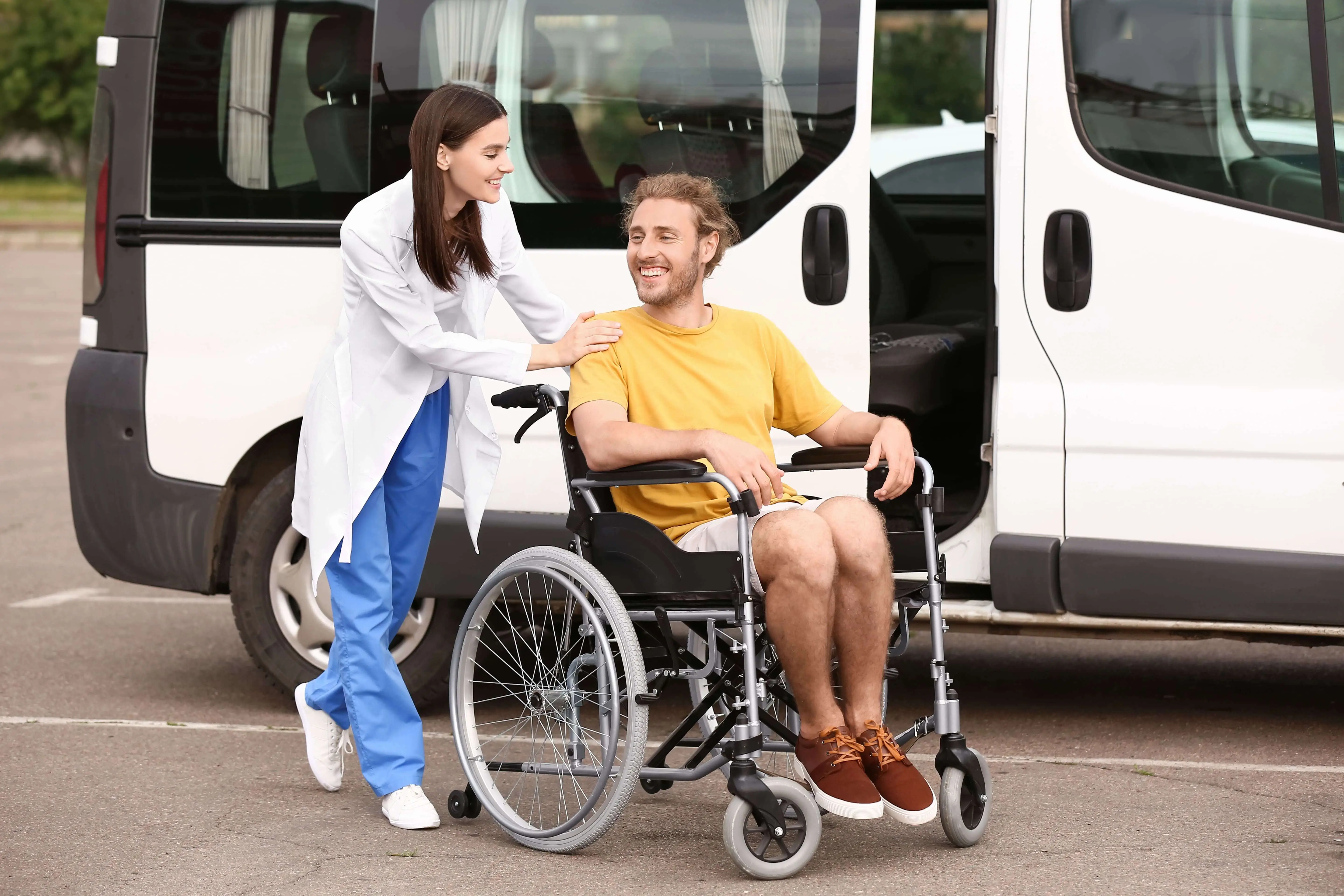 OC HomeCare caregiver assisting smiling male patient in a wheelchair for non-emergency medical transportation in Dana Point, CA