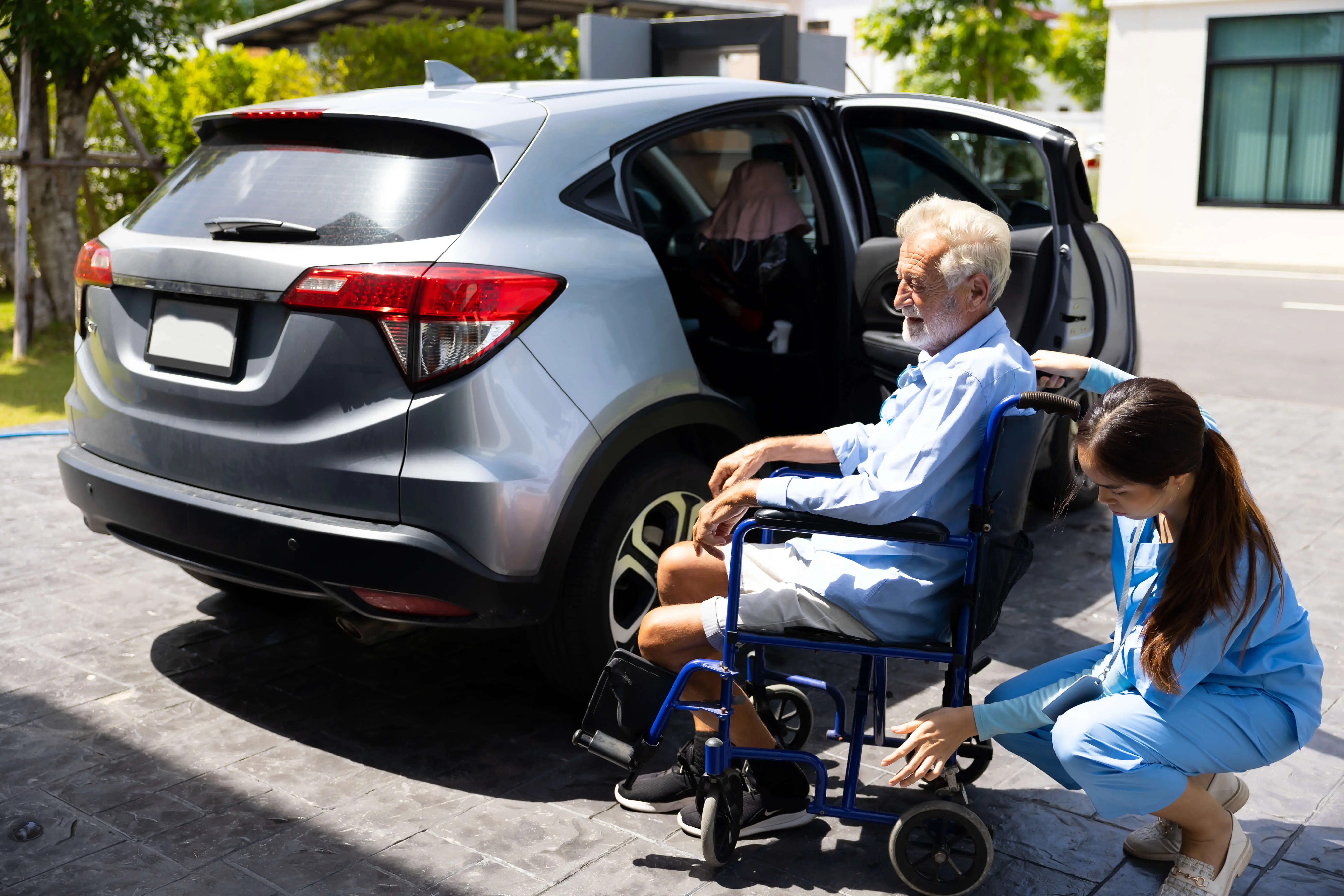 OC HomeCare caregiver assisting senior man in a wheelchair outside a transport vehicle for non-emergency medical transportation in Dana Point, CA