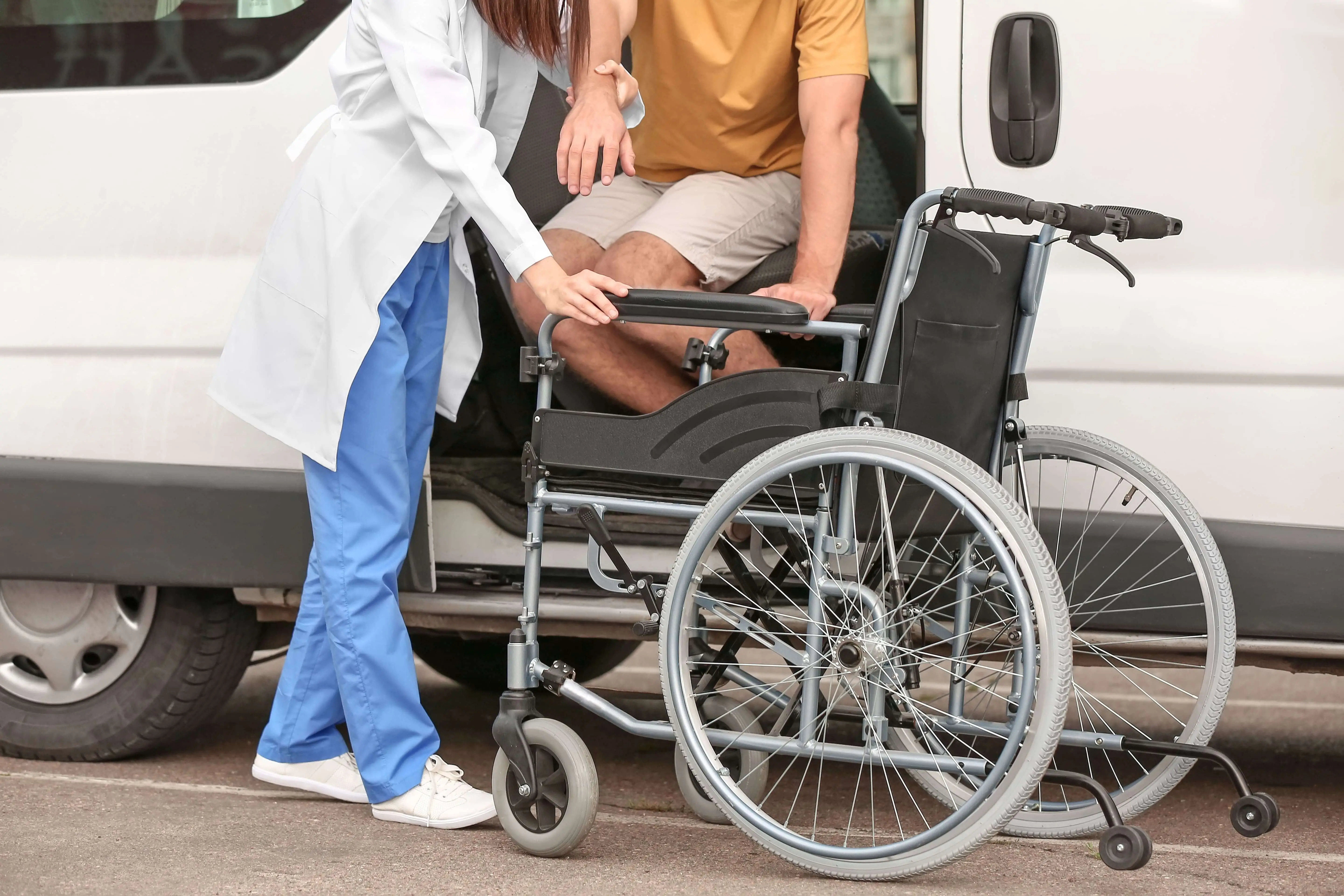 Dedicated caregiver assisting a patient into a wheelchair for safe, non-emergency medical transportation by Safe Link Transport in Dana Point, CA